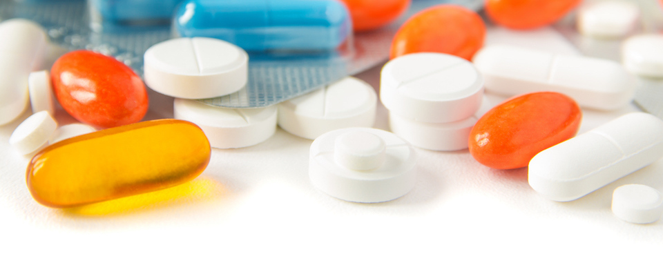 A photo white, orange, and yellow prescription pills used to represent a pharmacy benefits manager.